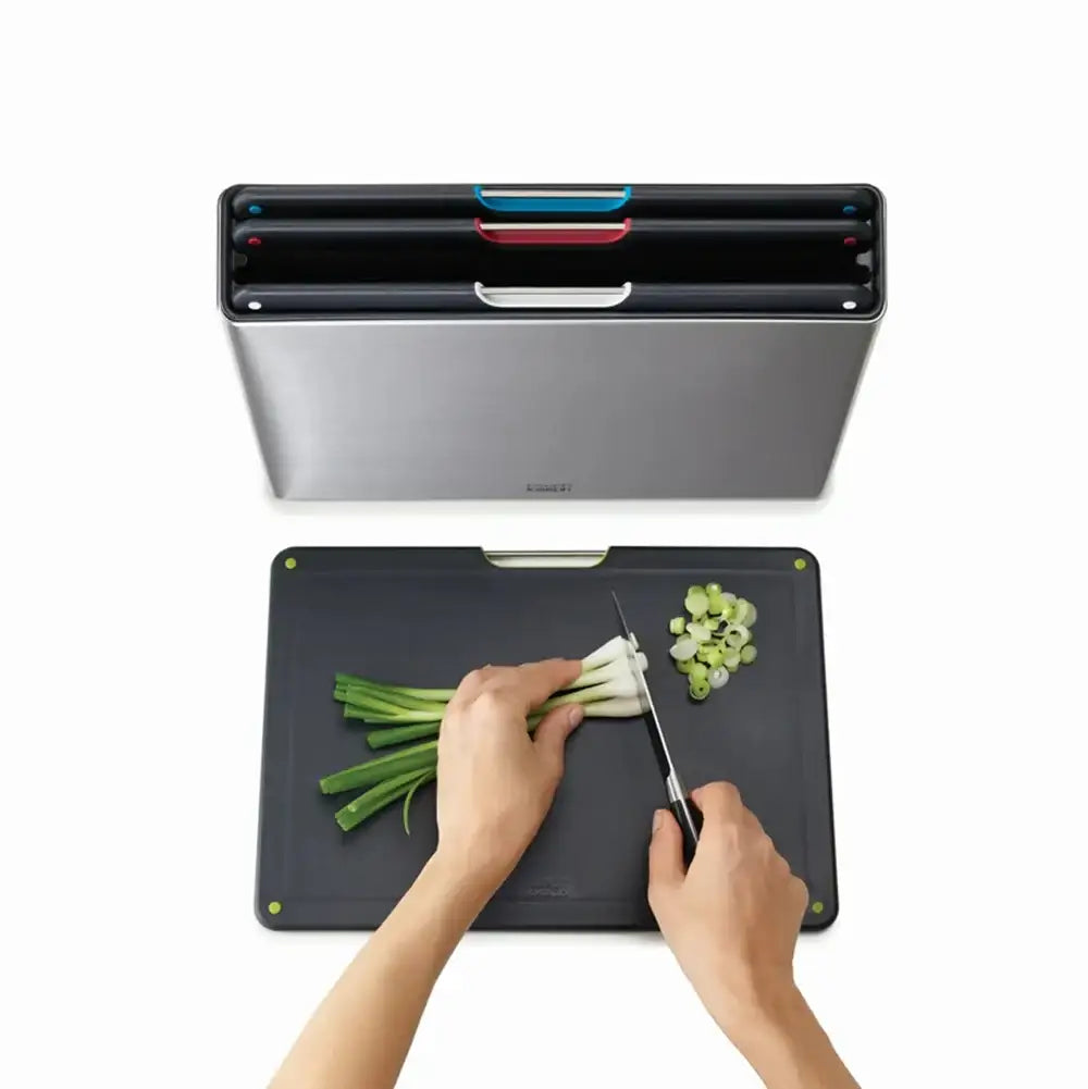 Person cutting vegetables on a cutting board with a knife, above a vacuum sealing device.
