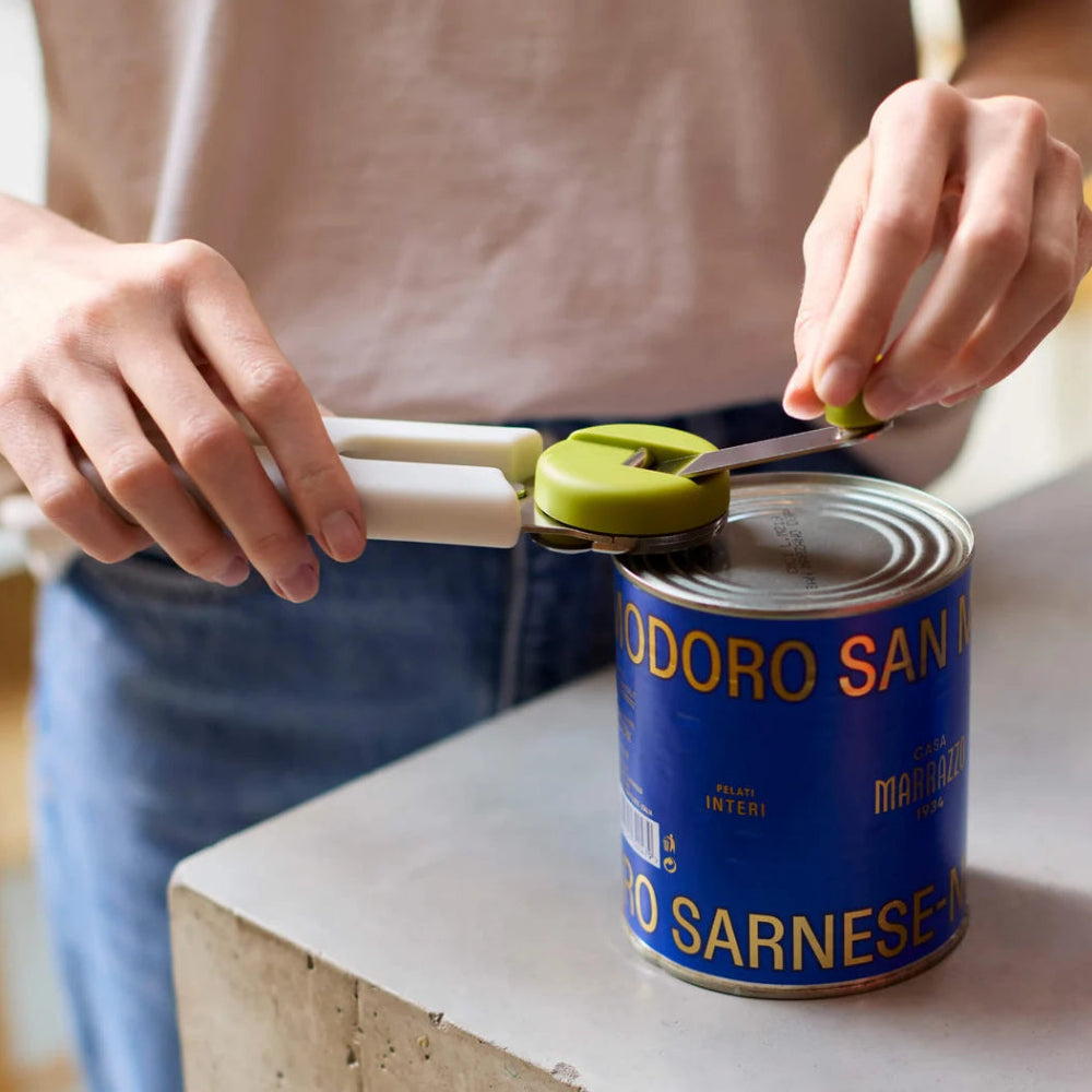 Person opening a can with a green and white can opener 