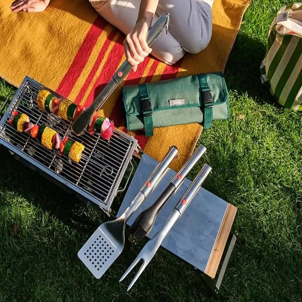Barbecue set with skewers and tools on a grassy area