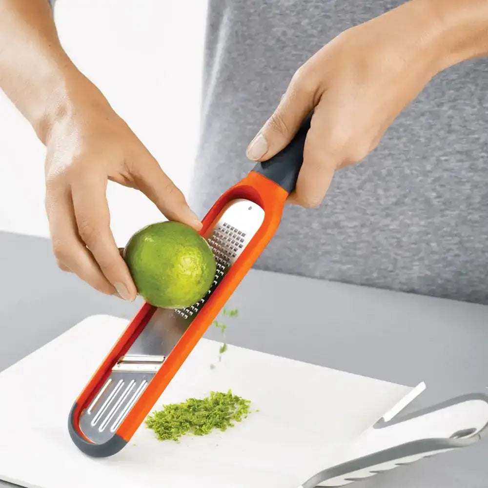 Person using a lime zester on a white cutting board.