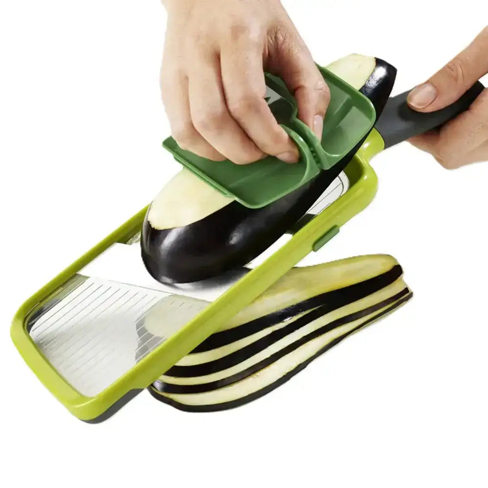 Person using a green and black mandoline slicer to slice an eggplant on a white background