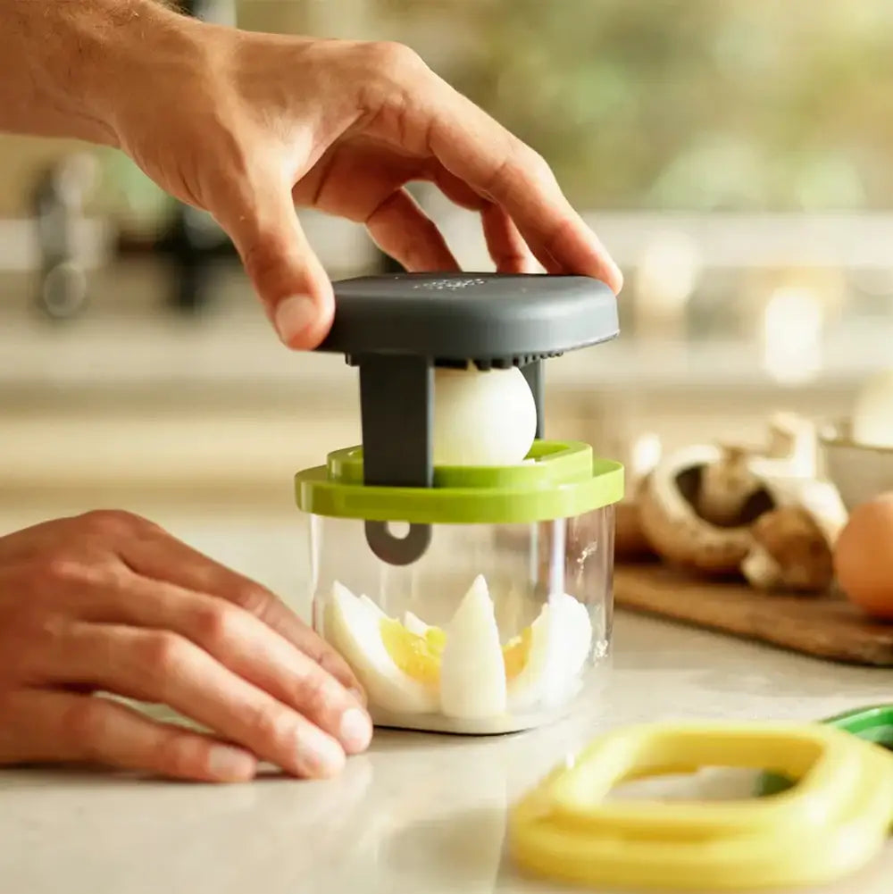 Person using a hand chopper with ingredients on a kitchen counter