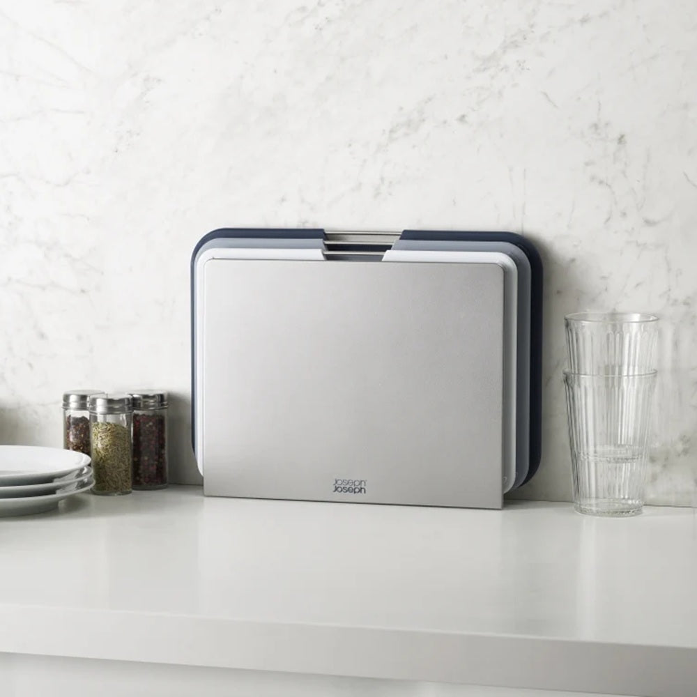 Stackable cutting boards on a kitchen counter with a white tiled wall background