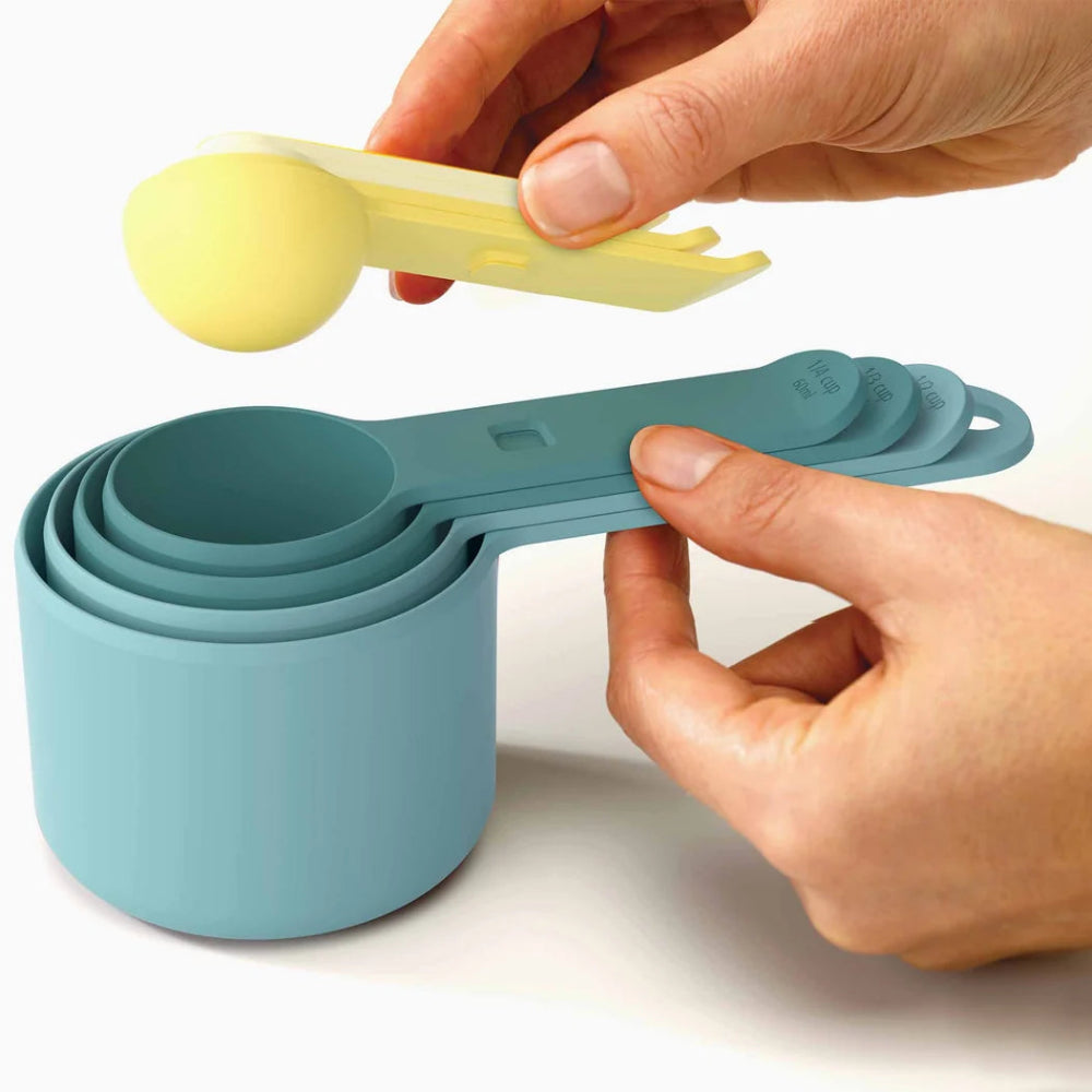 Hands holding blue and yellow measuring spoons on a white background 