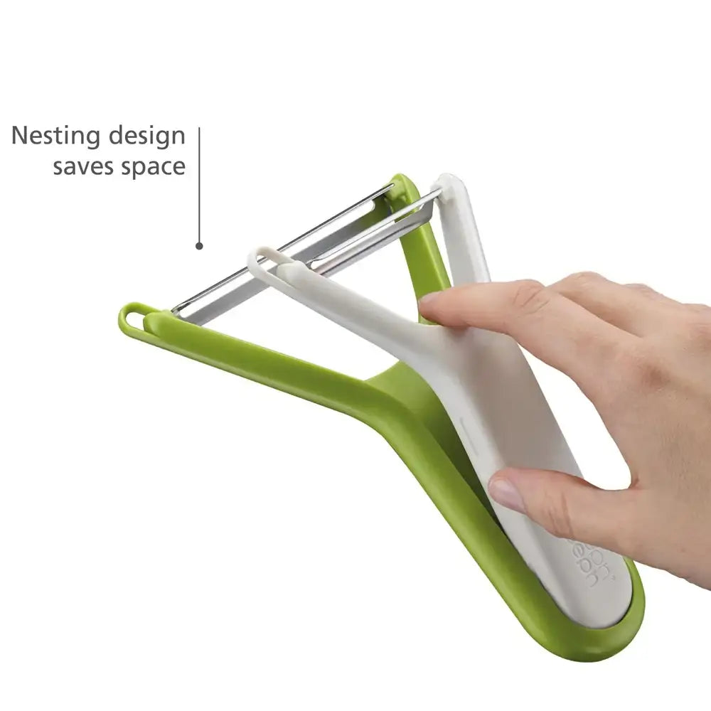 Green and white vegetable peeler with a hand holding it, on a white background.