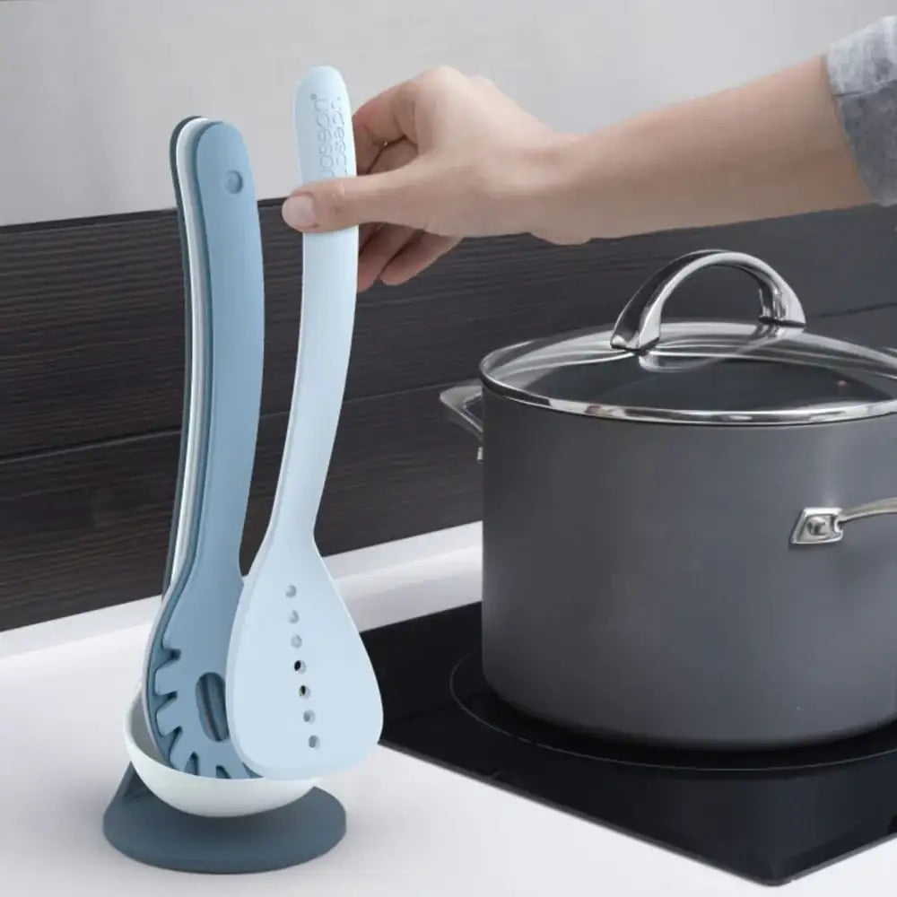 Two kitchen utensils held by a hand with a pot in the background