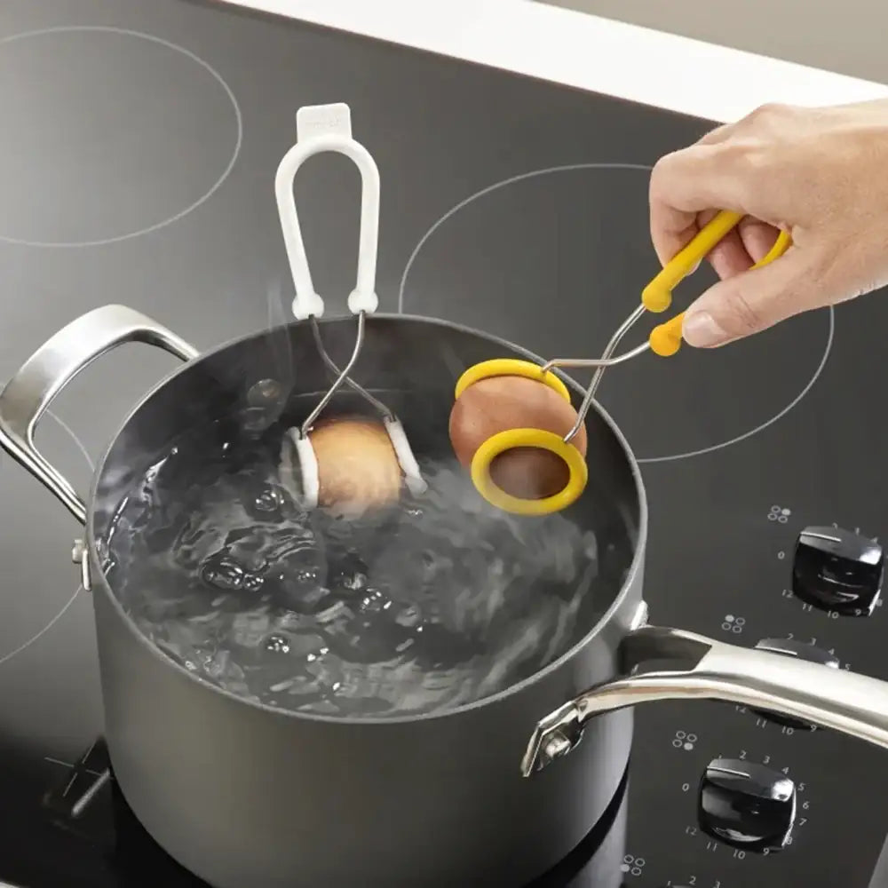 Person using a tool to remove a brownie from boiling water in a pot on a stove.