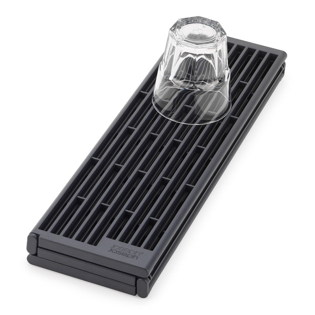 A black plastic bar drip tray with a slotted design, shown with an inverted clear glass on top, set against a plain white background.