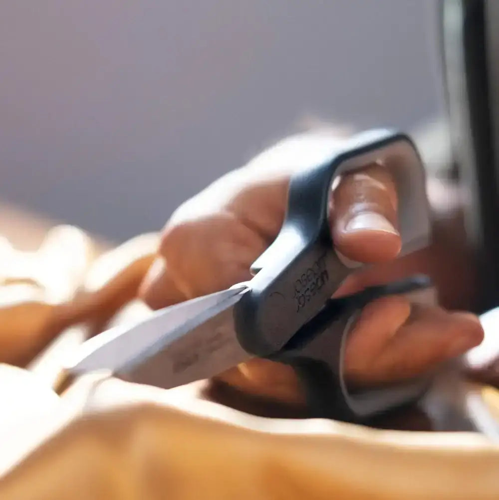Close-up of a hand holding a pair of scissors with a blurred background
