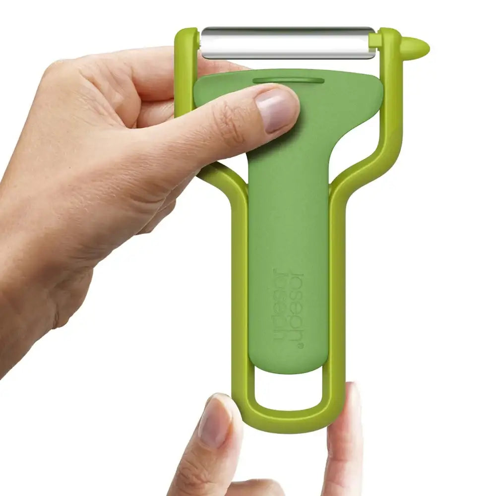 Green vegetable peeler held by a hand on a white background