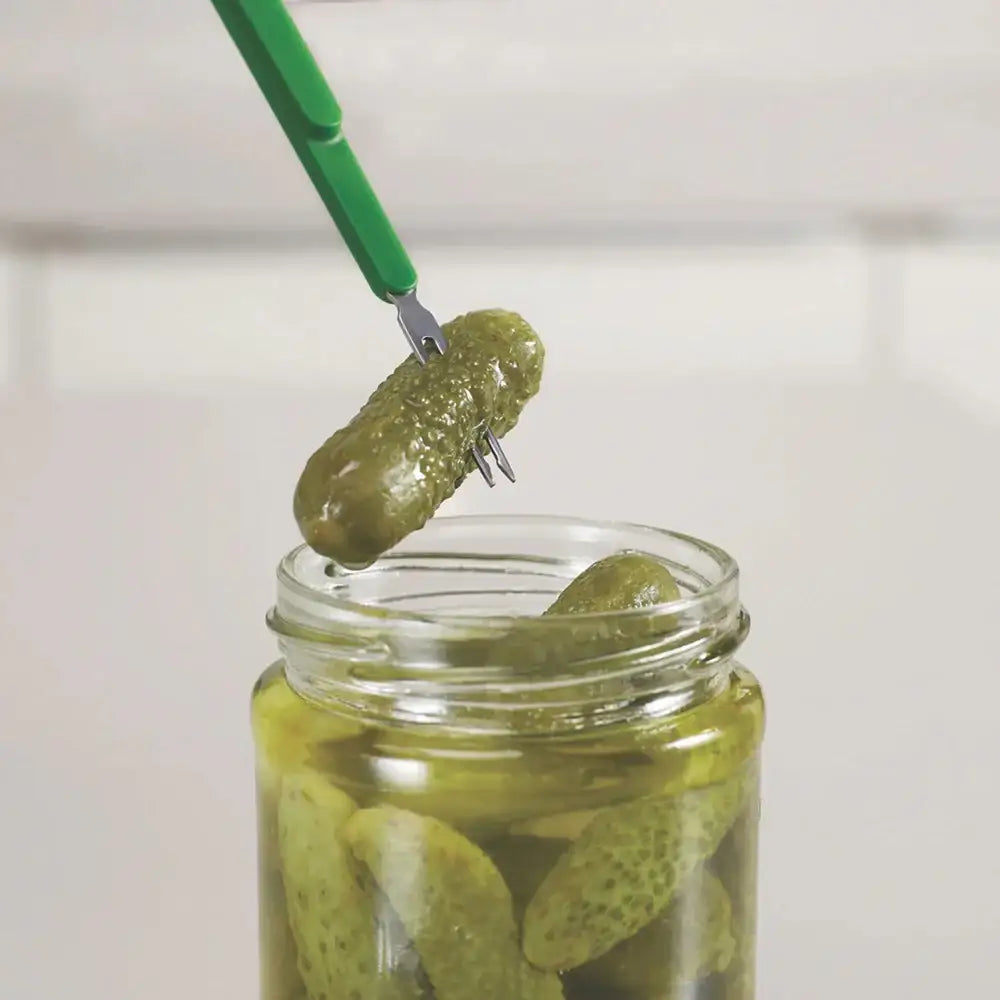 Jar of pickles with a green fork holding a pickle above it on a white background