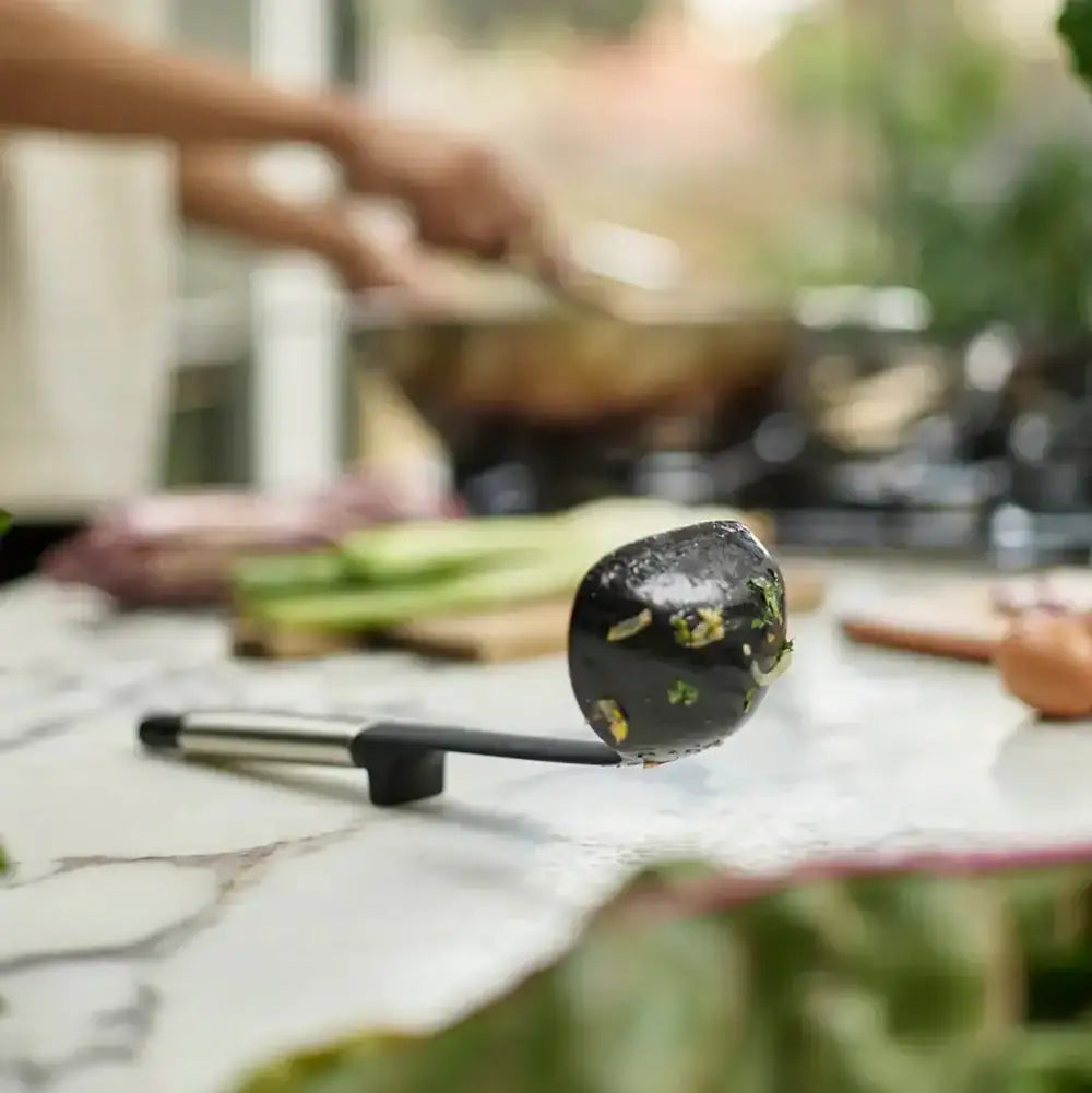 Person cooking outdoors with a wok and vegetables on a marble surface