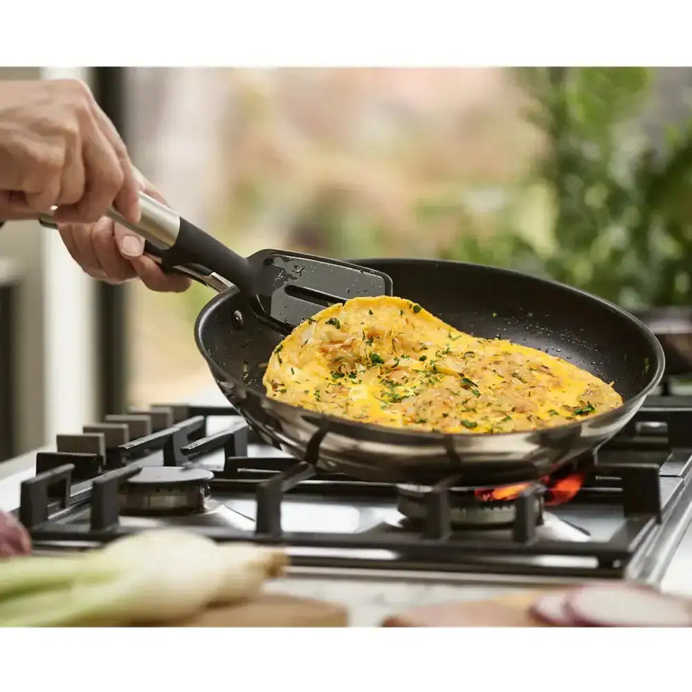 Person cooking an omelette in a frying pan on a stove with a spatula.