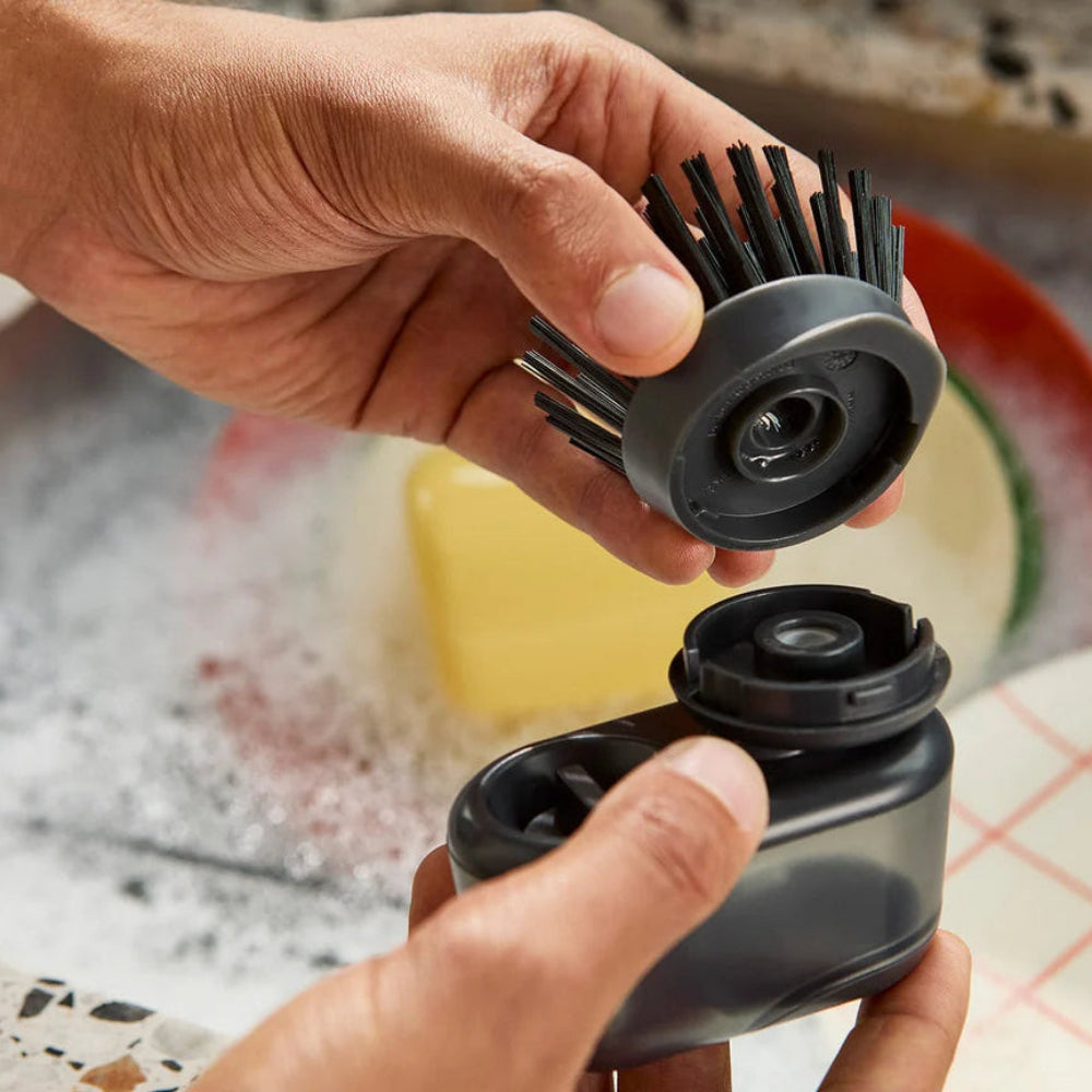 Person putting a brush attachment on a soap dispenser 