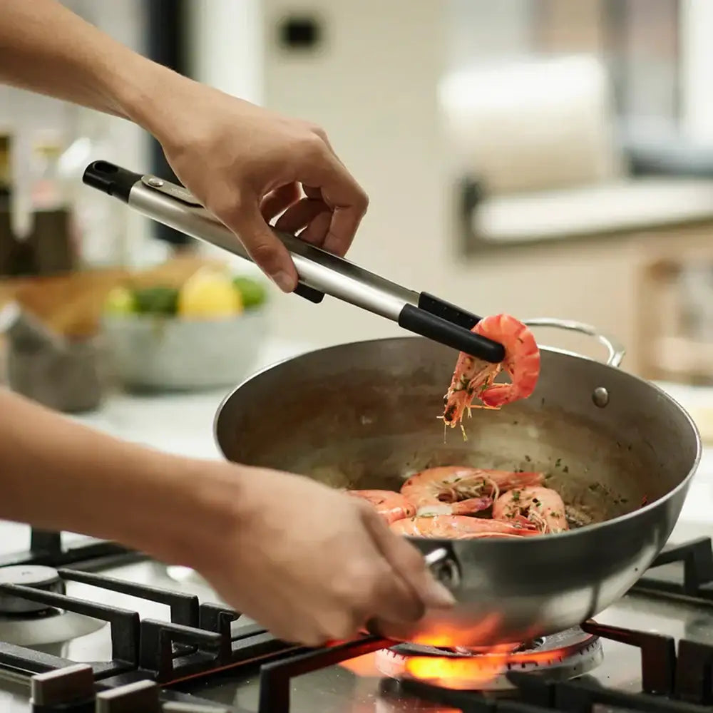 Person cooking shrimp in a pan on a stove