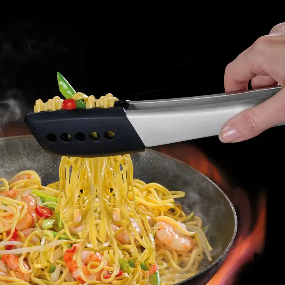 Person using tongs to serve pasta with shrimp and vegetables from a pan.