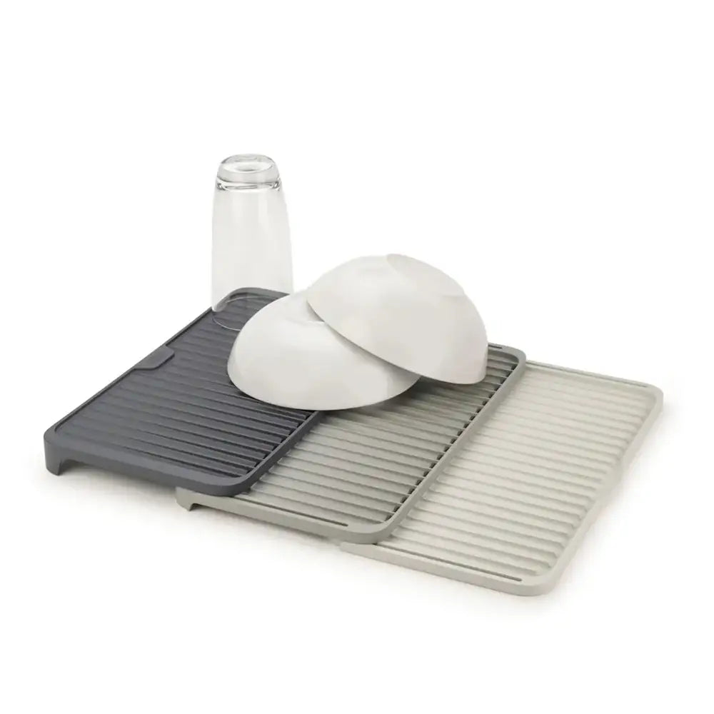 Gray and beige dish drying rack with dishes on a white background