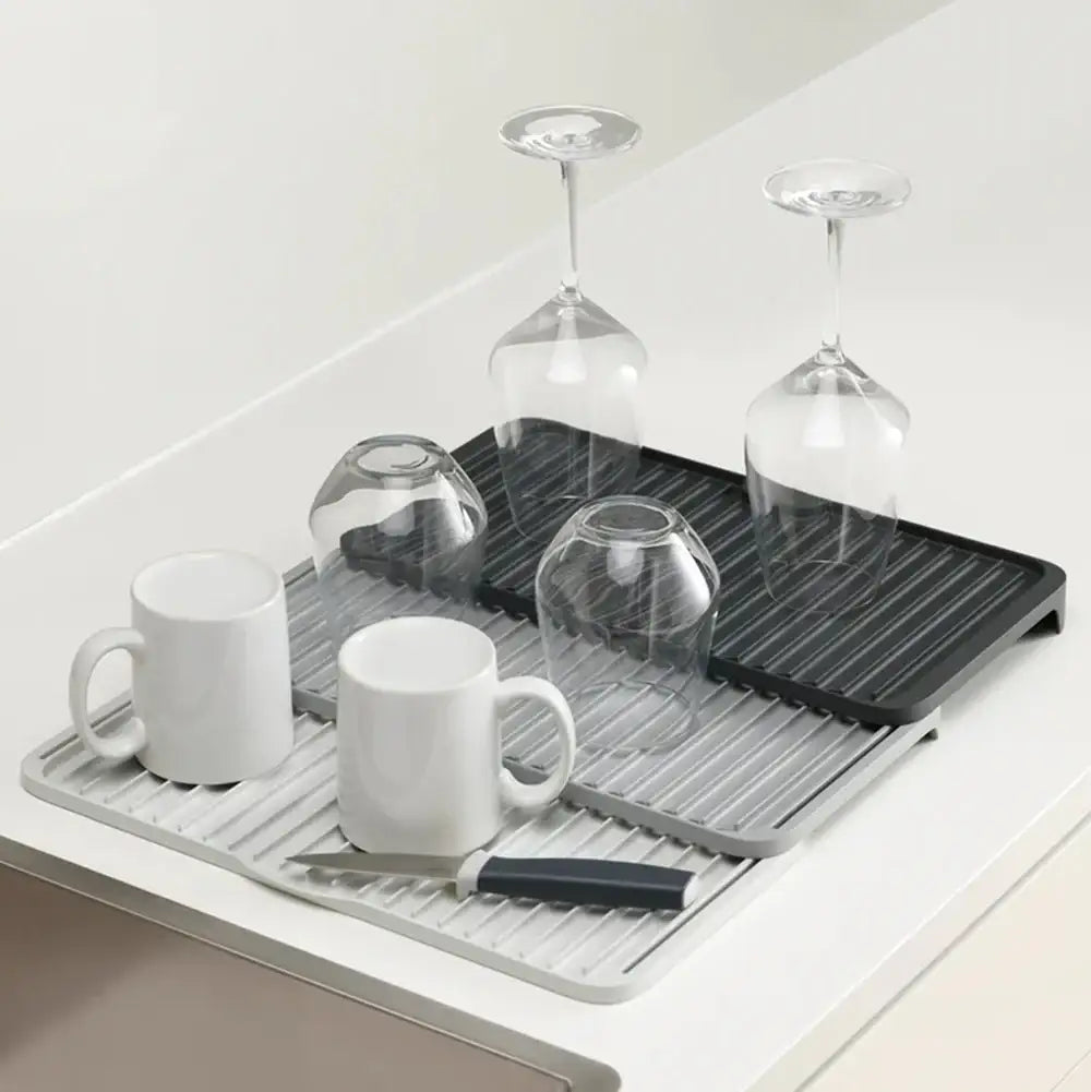 Dish drying rack with mugs, glasses, and a knife on a white surface