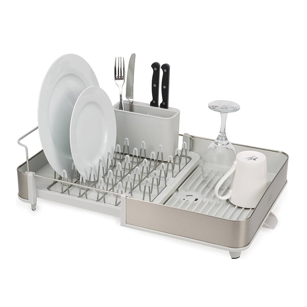 A stainless steel and white dish rack set shown on a white background, loaded with white plates, silverware, knives, a wine glass, and a white mug.