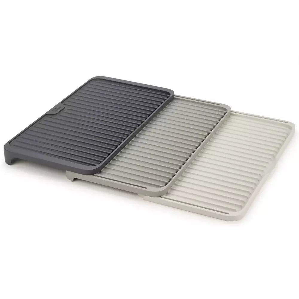 Three rectangular interlocked plastic draining mats in dark gray, medium gray, and light gray, arranged overlapping on a white background.