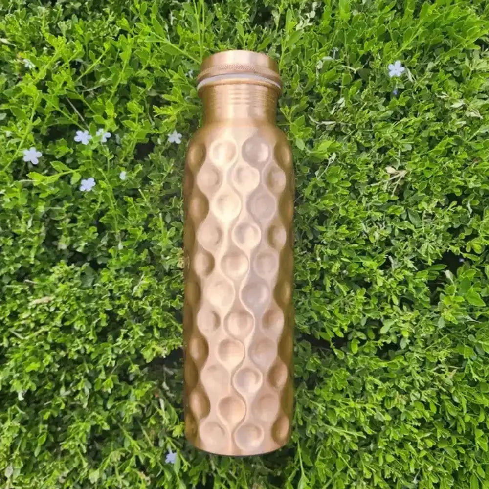 Bronze honeycomb-patterned water bottle on a green grass background