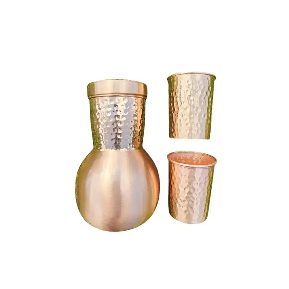 Copper pitcher and two cups with hammered finish on a white background