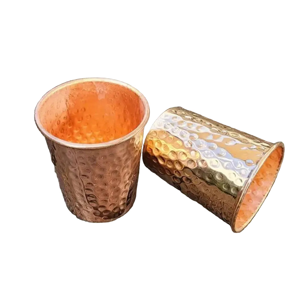 Two copper cups on a wooden surface