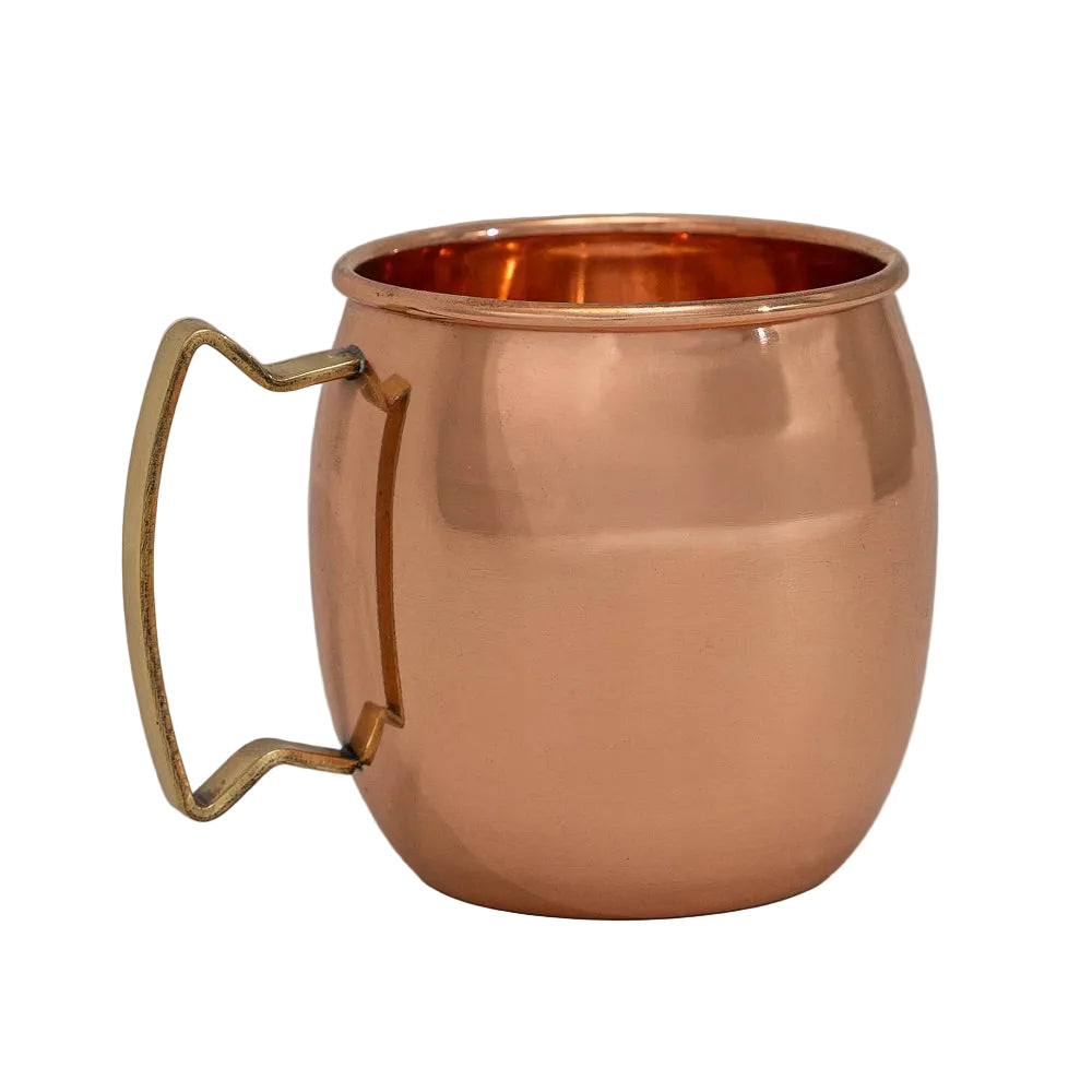A classic Moscow Mule mug made of polished copper with a curved, twisted brass handle, shown on a neutral light gray background.