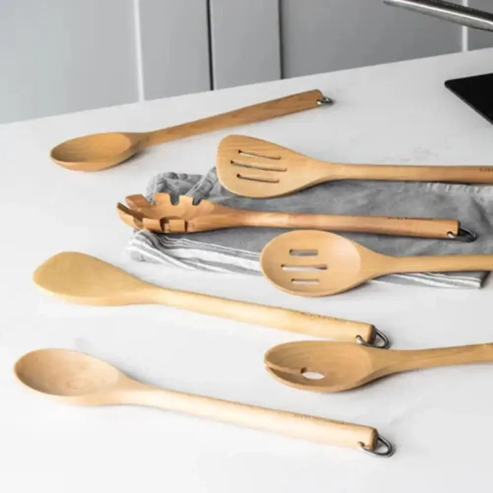 Set of wooden kitchen utensils on a white surface with a neutral background