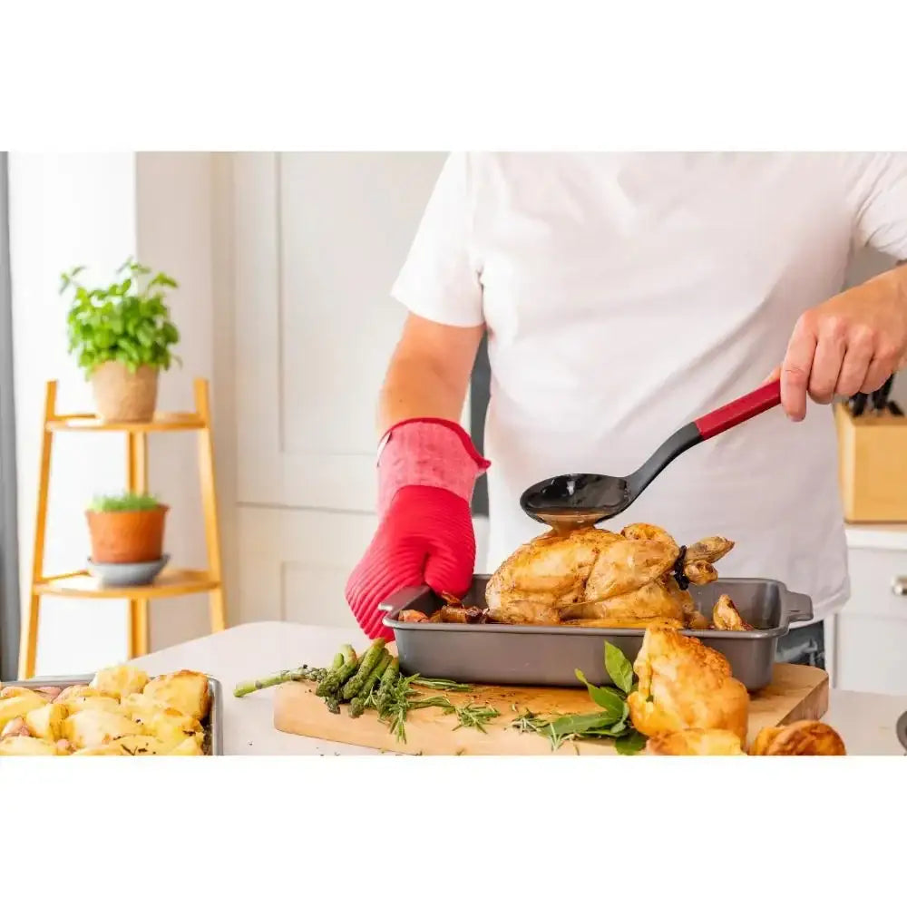 Person cooking a roasted chicken in a kitchen with various ingredients on the counter.