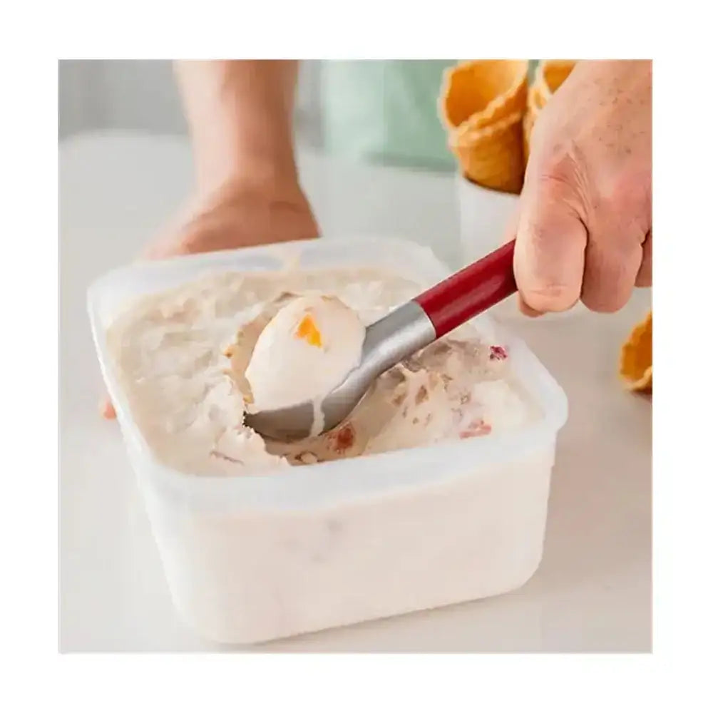 Person scooping ice cream from a container with a red-handled spoon.