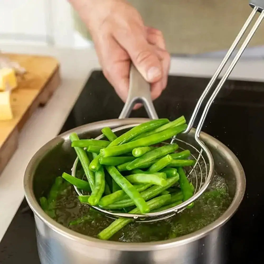 Green beans being drained from a pot with a metal strainer.