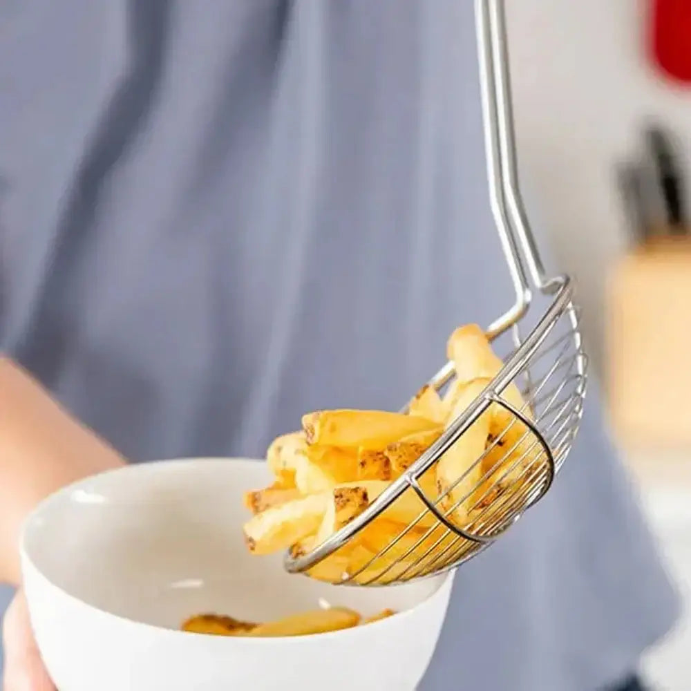 Metallic strainer filled with french fries being lifted from a white bowl.