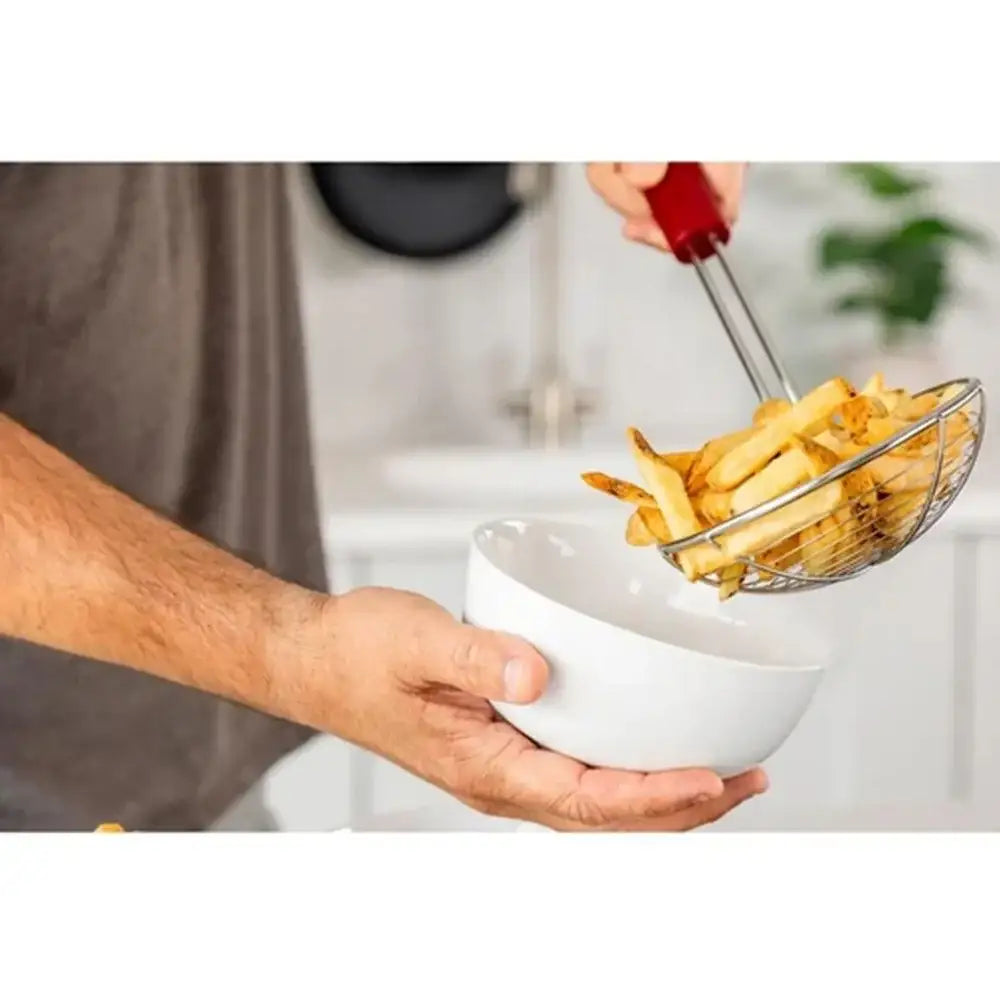 Person transferring French fries from a strainer into a white bowl.