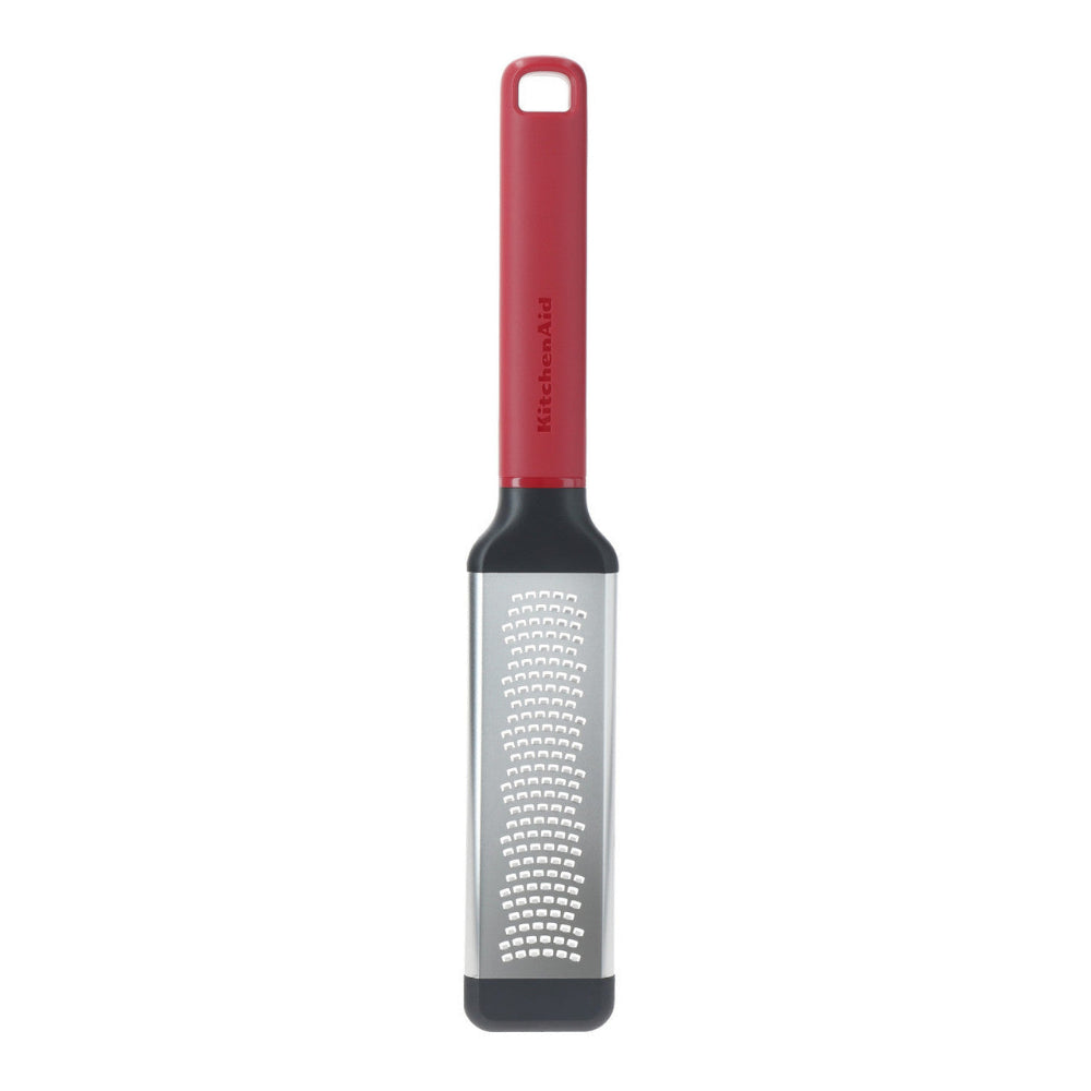 Metal grater with red handle on a white background