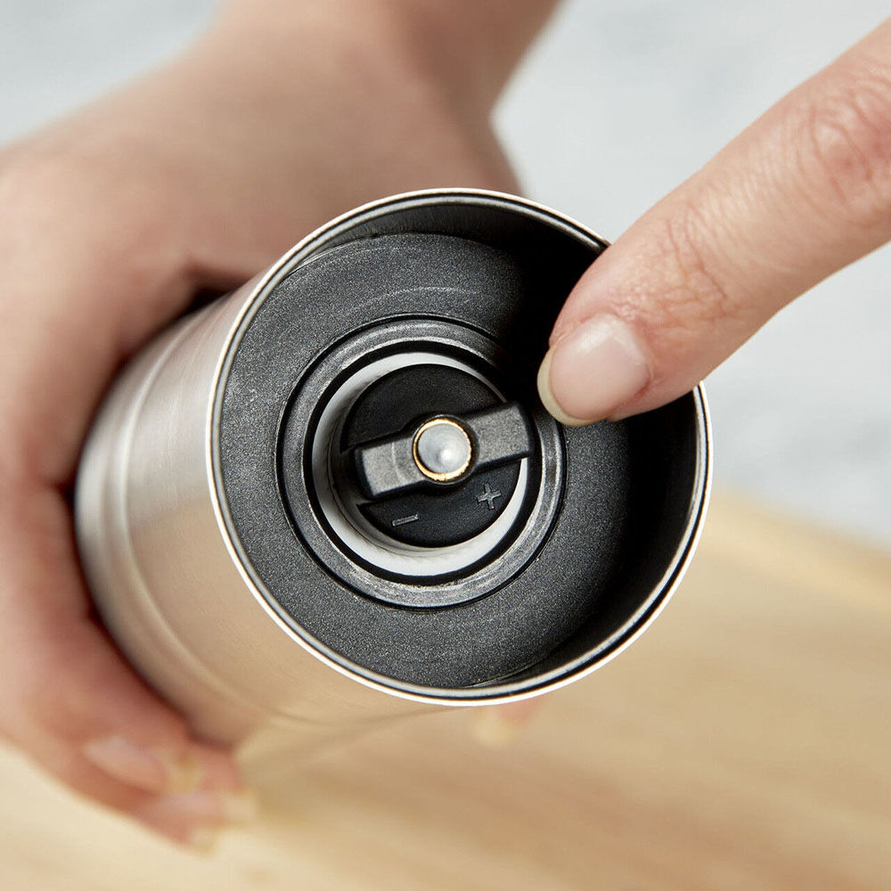 Close-up of a hand holding a metallic object with a blurred background