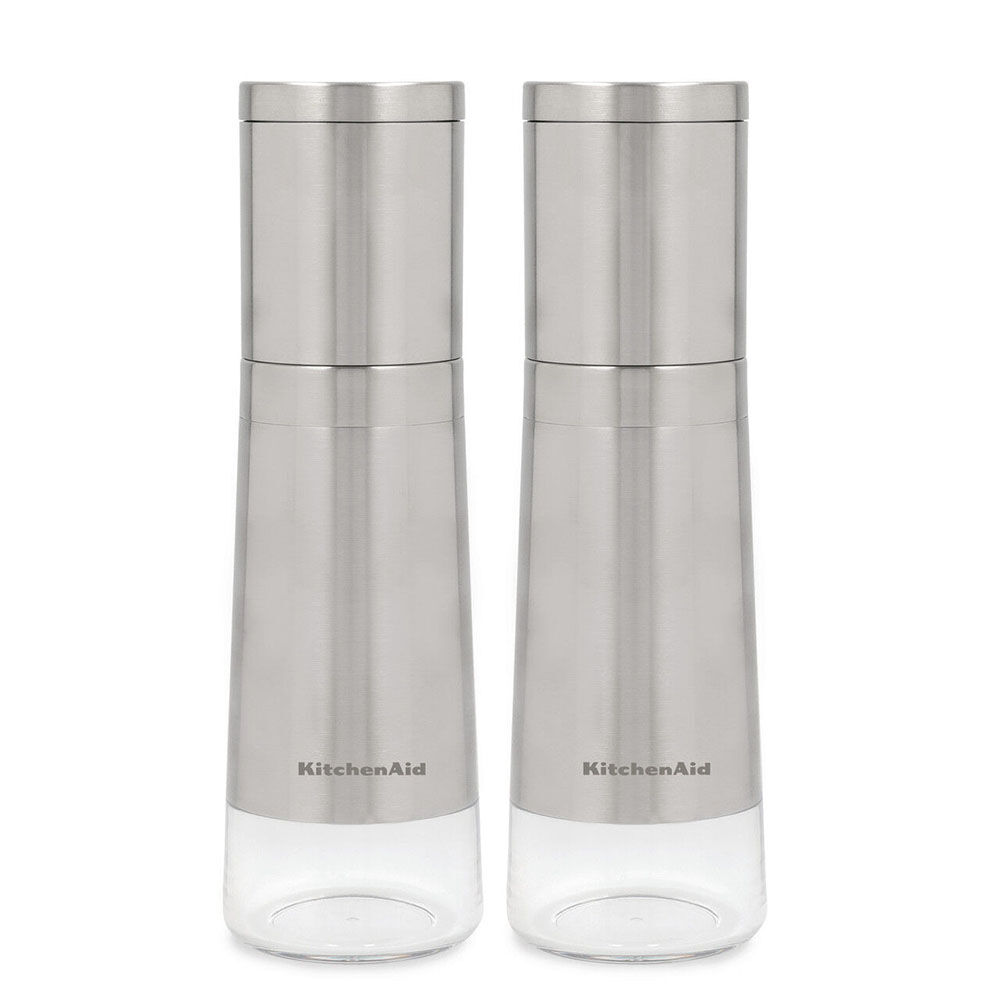 Two KitchenAid stainless steel and clear glass salt and pepper mills standing side by side on a white background.
