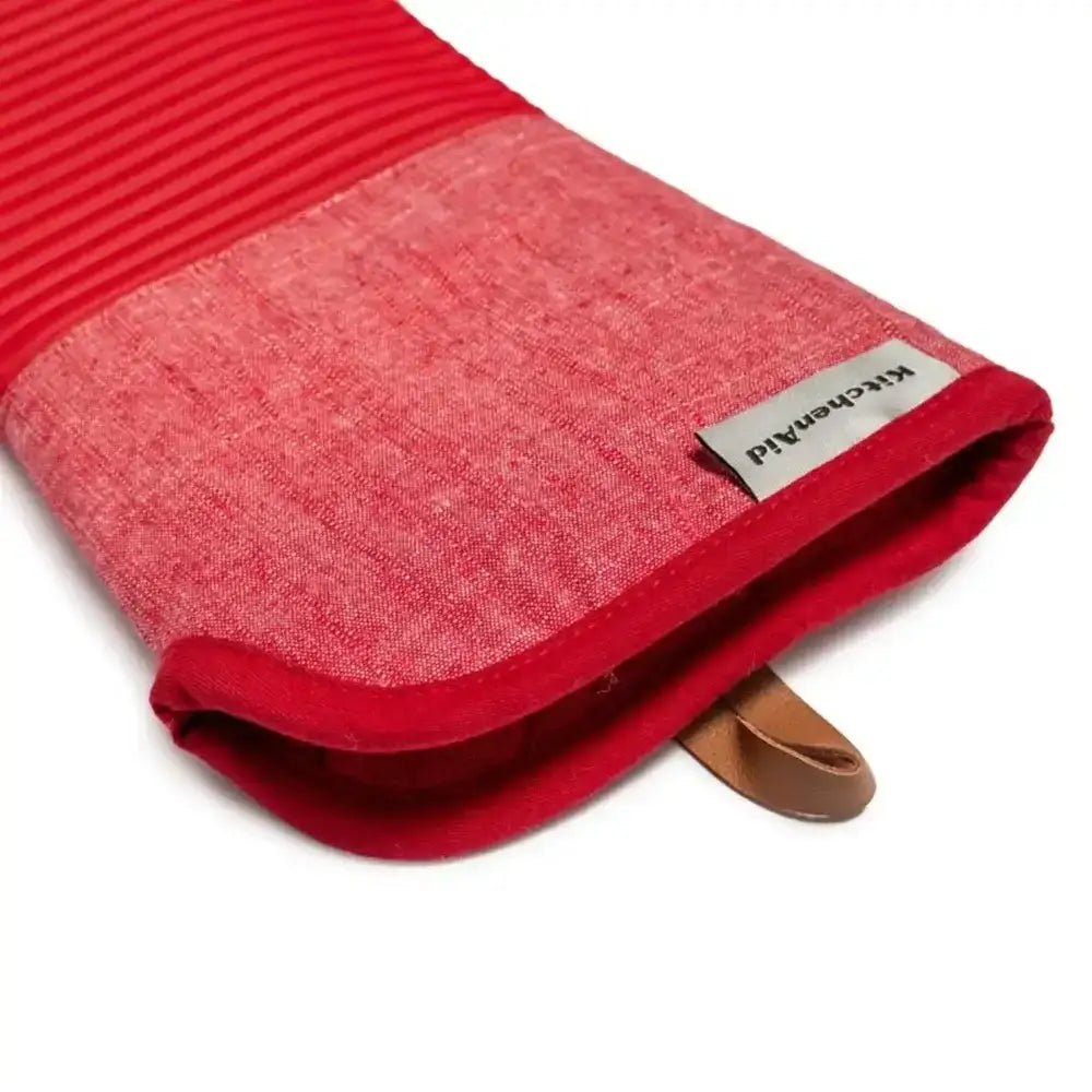 Red oven mitt with a brown handle on a white background