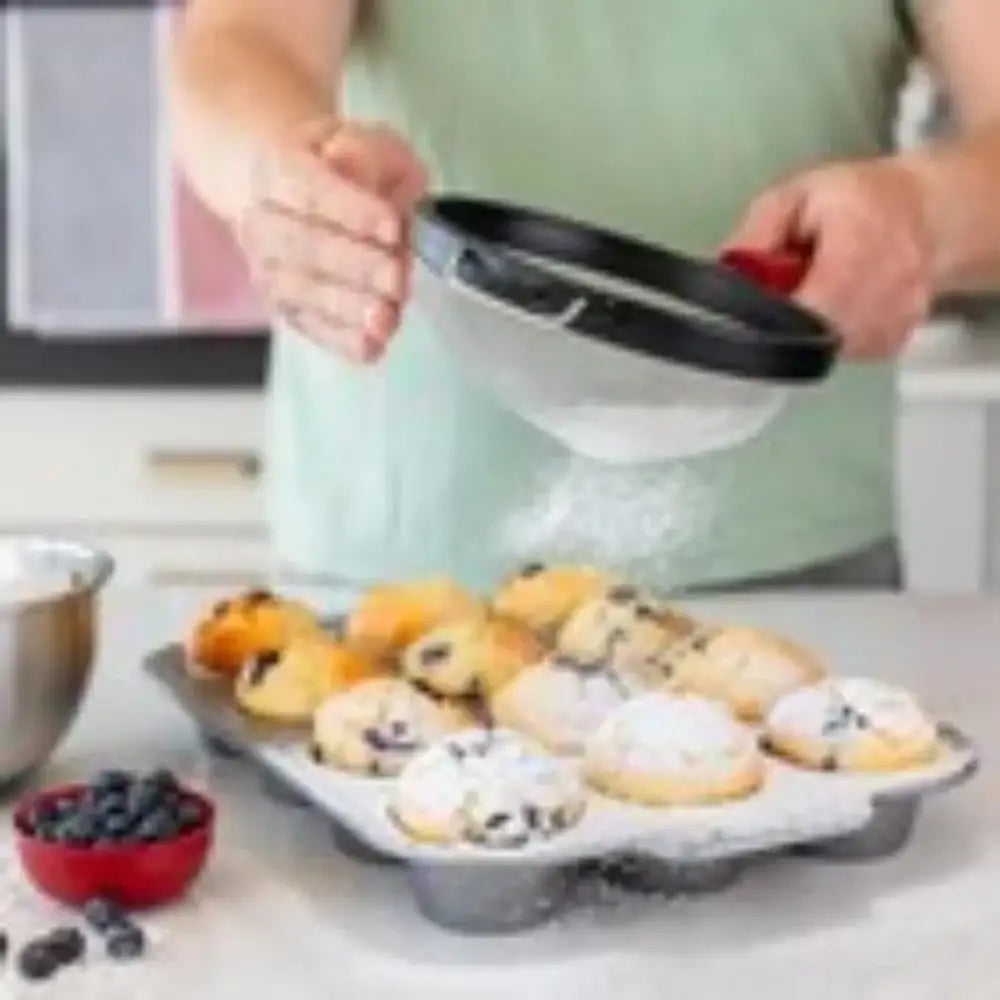Person using a kitchen tool to remove cookies from a baking tray on a kitchen counter.