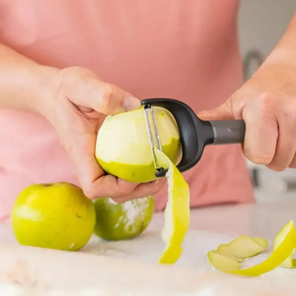 Person using a peeler to peel an apple with a blurred background