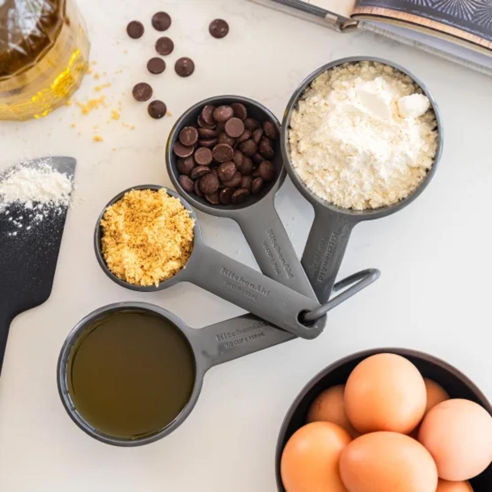Set of measuring cups with ingredients on a white surface