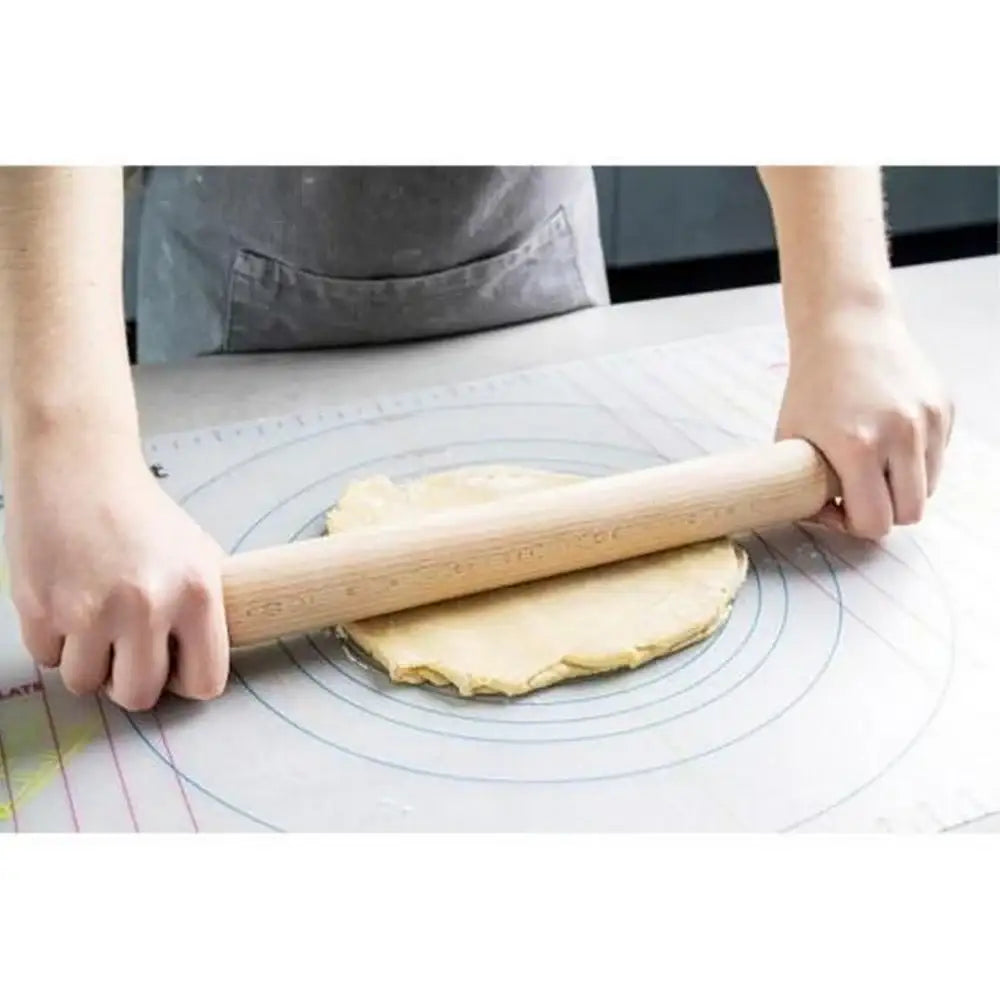 Person rolling out dough with a wooden rolling pin on a pastry mat.