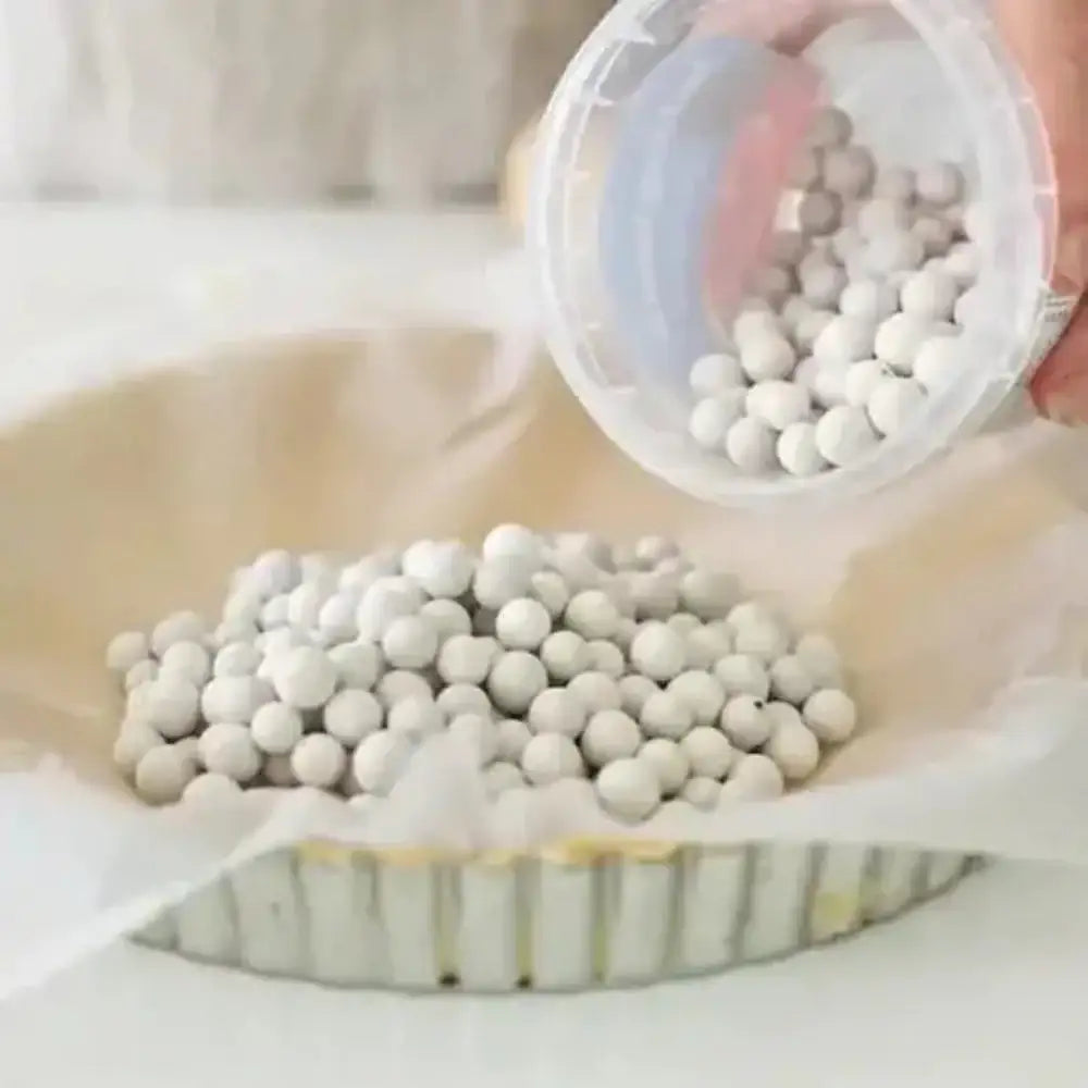 White spherical beads being poured from a container onto a surface.