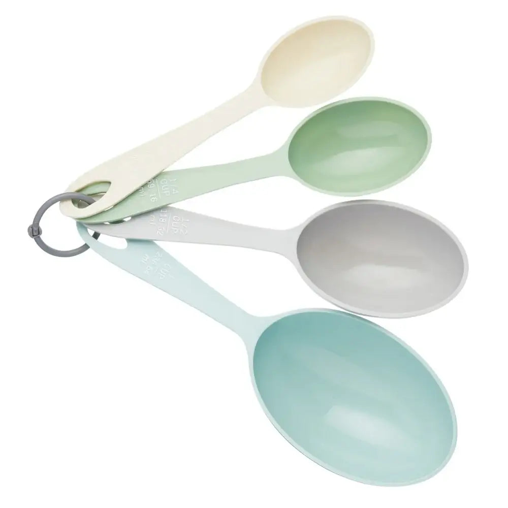 Set of four measuring spoons in different colors on a white background
