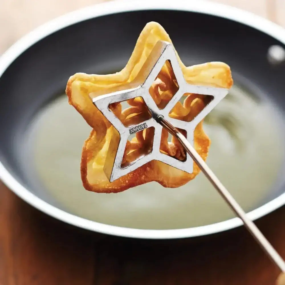 Star-shaped fried food being lifted out of a frying pan with a metal spatula.
