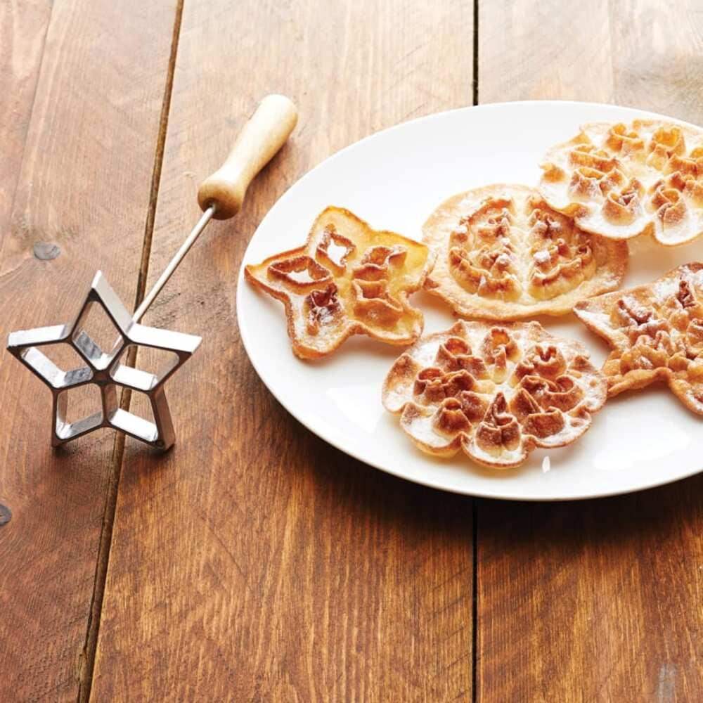 Star-shaped cookie cutters with star-shaped cookies on a plate on a wooden surface