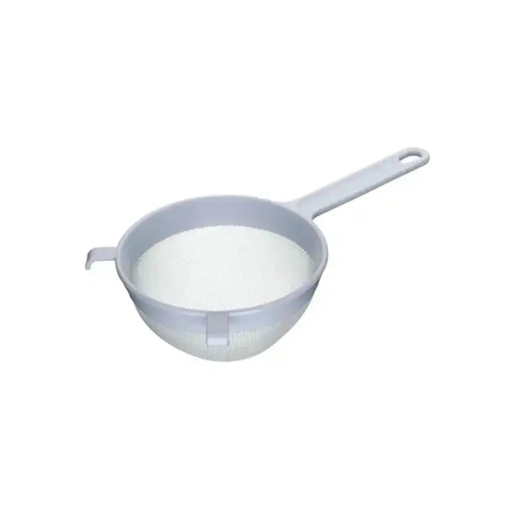 Small strainer filled with white powder on a white background