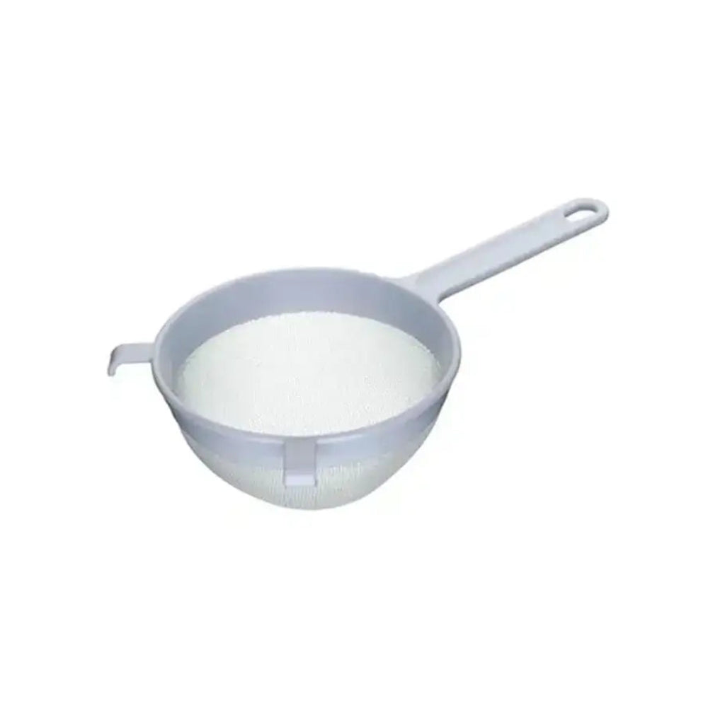 Small strainer filled with white powder on a white background
