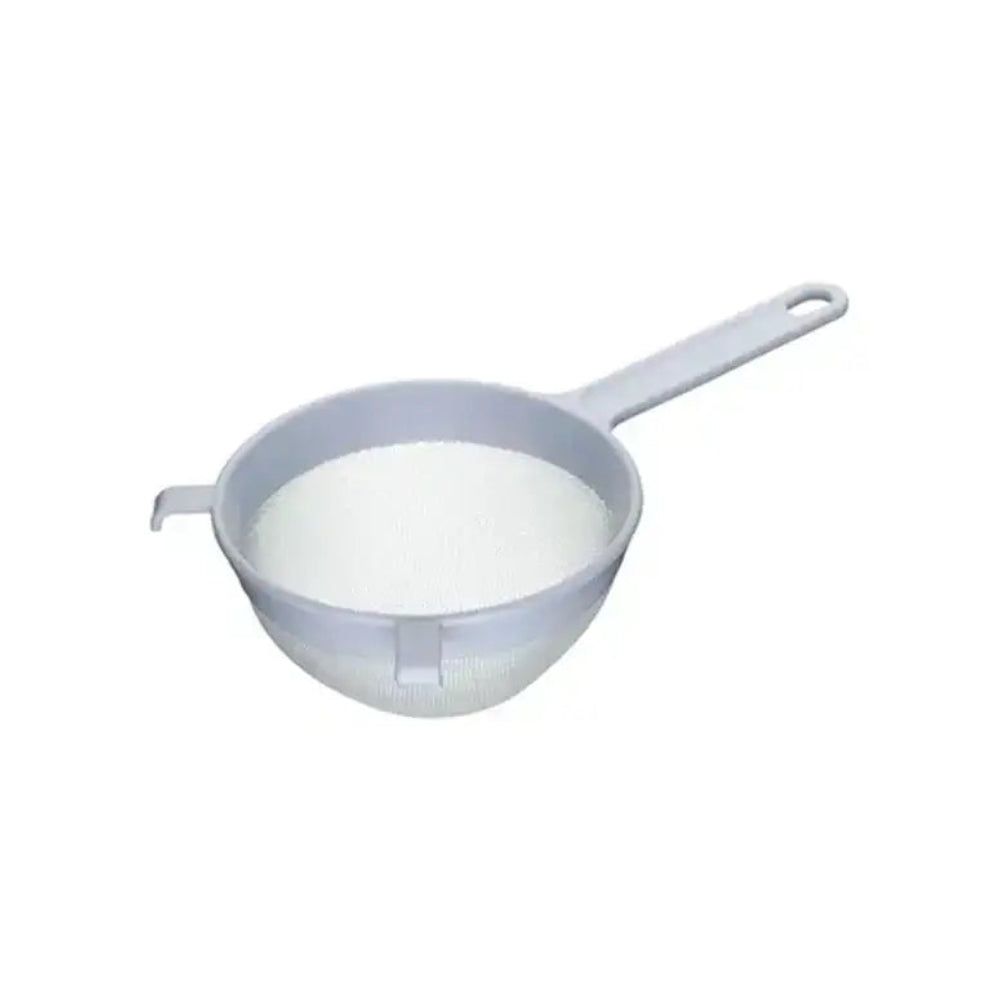 Small strainer filled with white powder on a white background