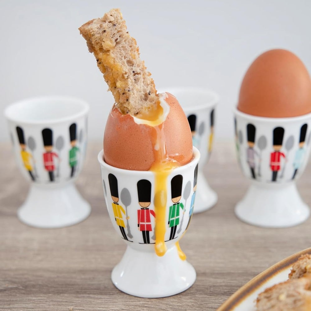 Egg in a decorative holder with a piece of bread on top, surrounded by other similar holders.